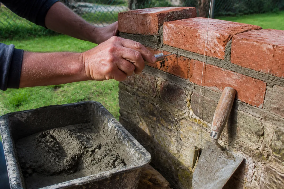 Rangée de briques et joints de mortier frais sur la reprise d&rsquo;un mur de jardin