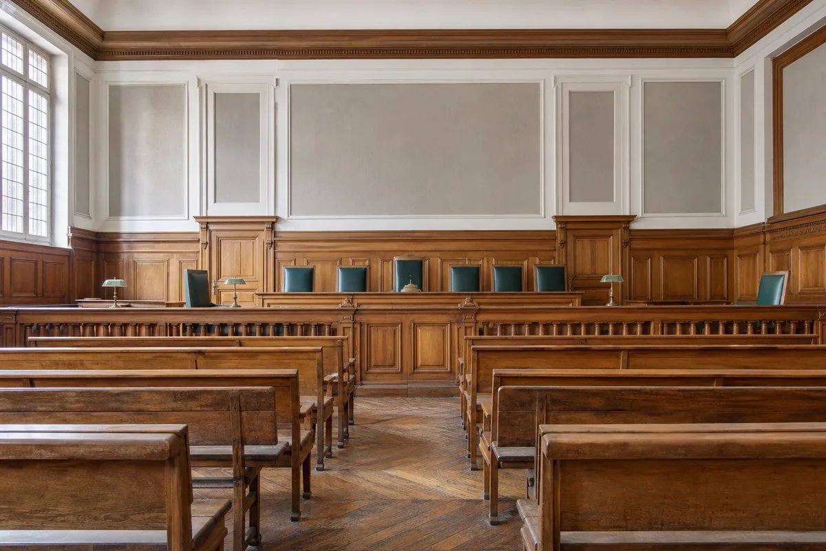 Salle d’audience vide d’un tribunal de commerce français avec bancs de bois clair