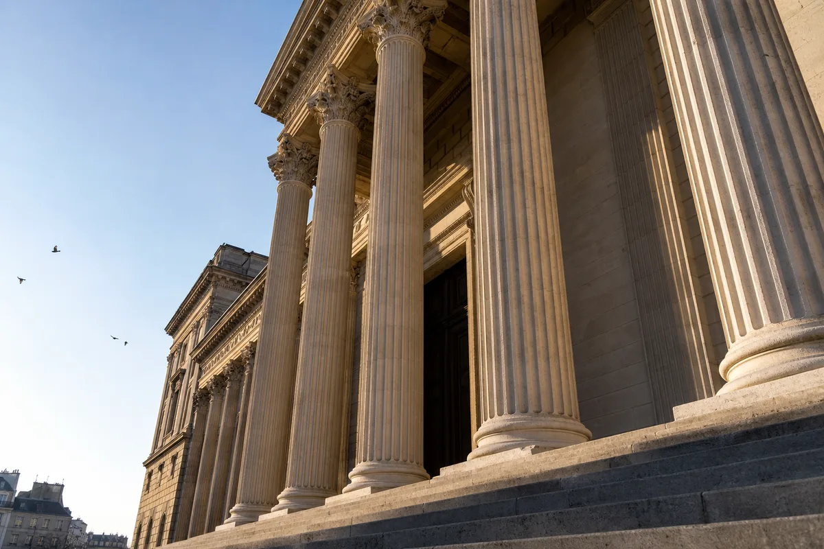 Colonnes de pierre d’un palais de justice français sous une lumière matinale