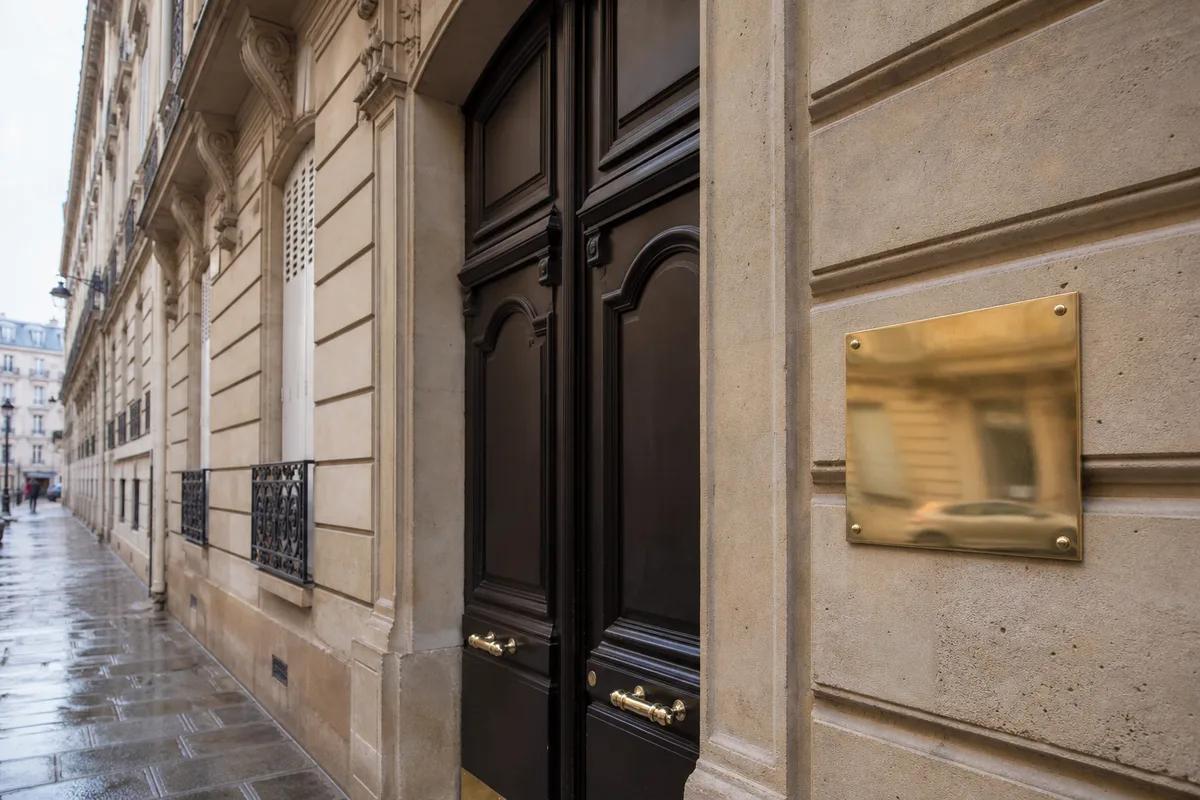Façade haussmannienne avec plaque professionnelle en laiton près d’une porte cochère