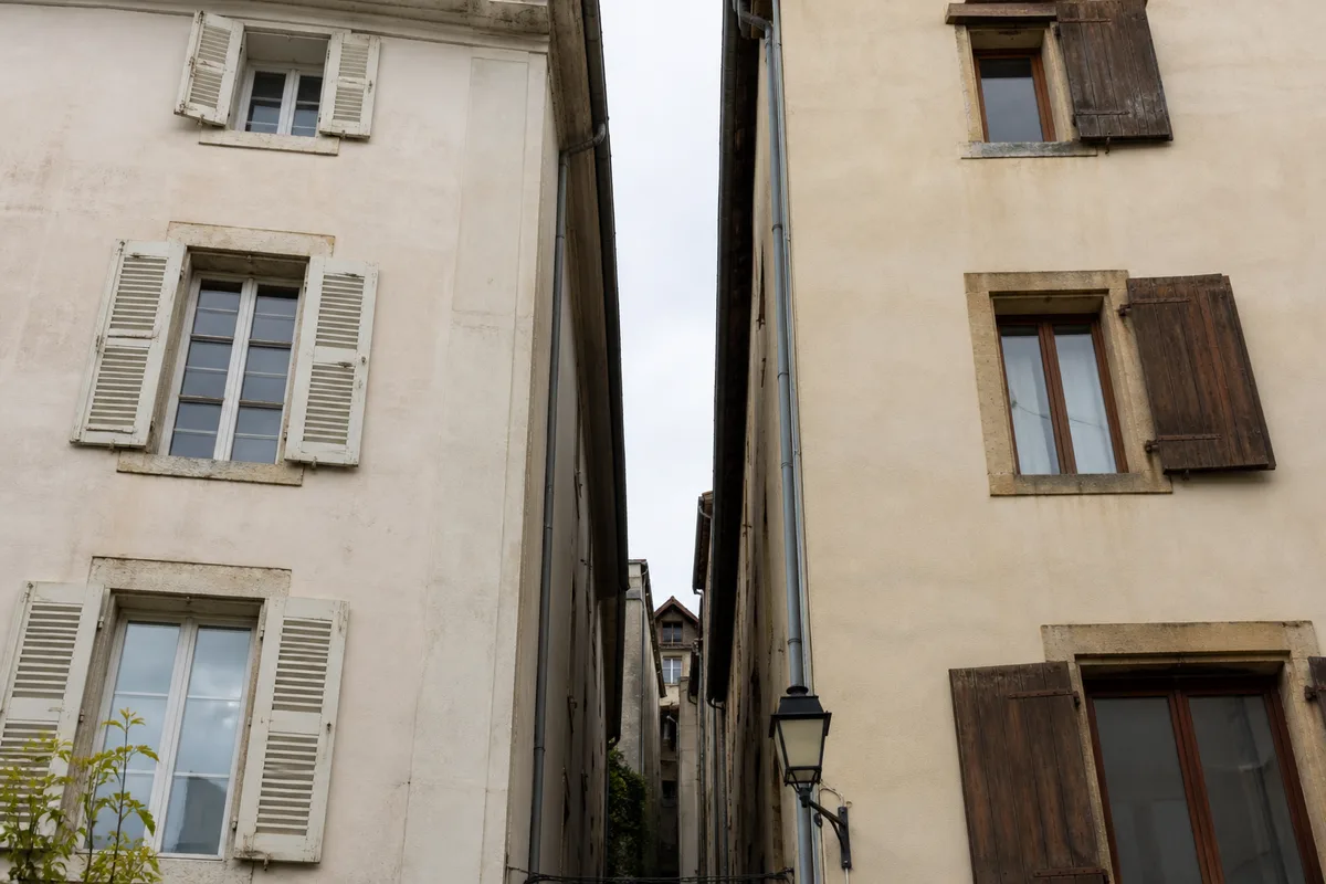 Façades mitoyennes aux enduits clairs séparées par une venelle étroite